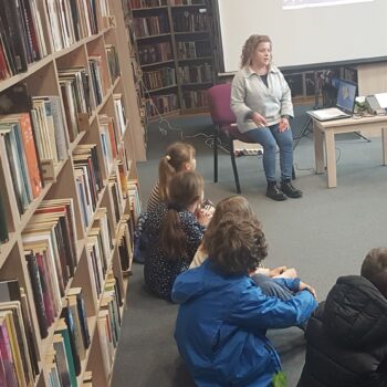 Odkrywcy na tropie przygód. bibliotekarka i dzieci na podłodze