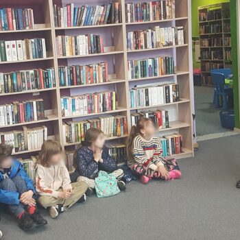 Odkrywcy na tropie przygód. bibliotekarka i dzieci na podłodze