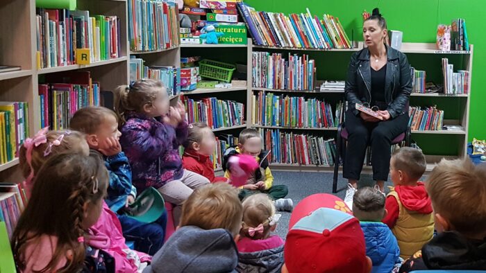 Spotkanie z animatorem kultury. Kobieta czyta dzieciom w bibliotece.