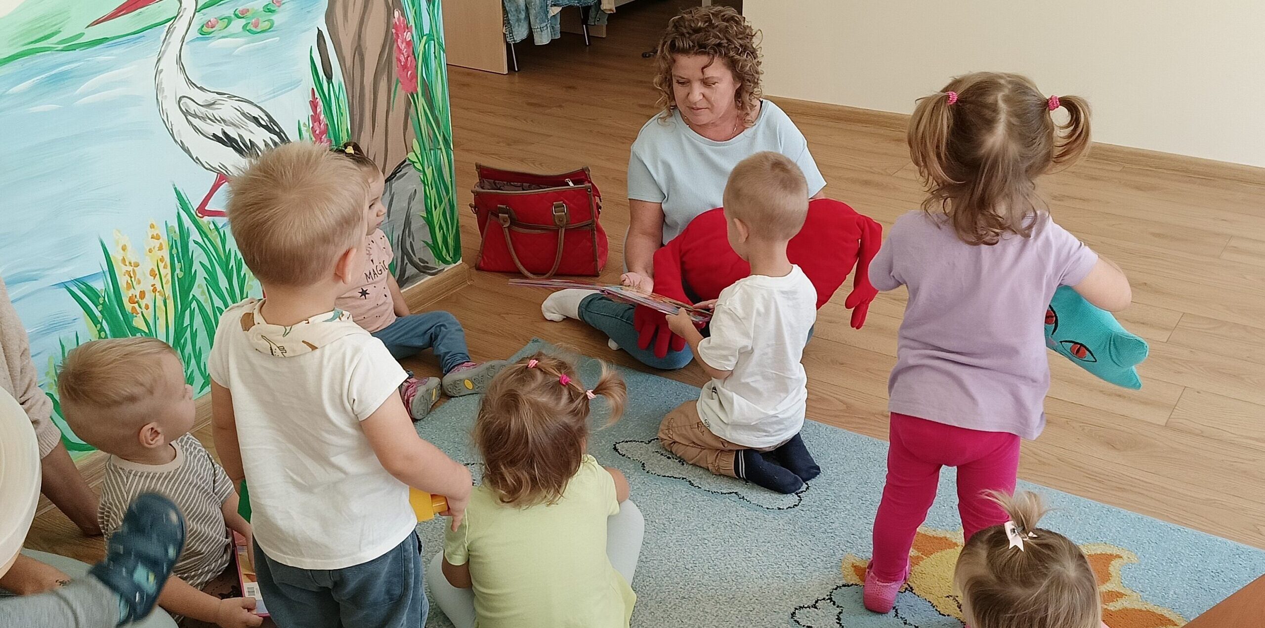 Dzień głośnego Czytania. Kobieta i dzieci czytają na podłodze